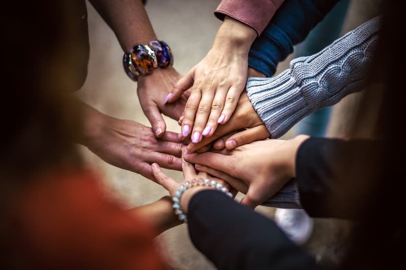 people in a circle with their hands in the middle